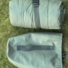 Compact waterproof sleeping bag with built-in hypothermia monitoring pockets packed for travel